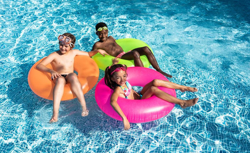 kids smiling and happy in the pool on a sunny summer day