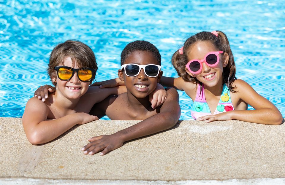 kids smiling and happy in the pool on a sunny summer day